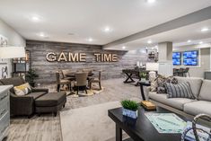 a living room filled with furniture next to a kitchen and dining room table in front of a game time sign