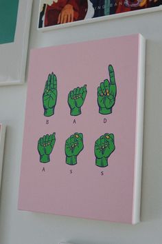 there is a pink and green painting on the wall with different hand gestures in front of it