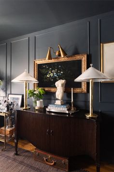 a living room with two lamps and a painting on the wall over a console table