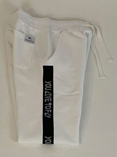 White YLF Joggers. Jogger pants feature YLF logo branding tape down the sides. Made from ultra-soft comfort cotton fleece with side slash pockets, back right pocket. Also feature a gusseted crutch for ultimate comfort and style and rib-knit ankle cuffs. Classic elasticized waistband and drawstring.

 

 

 	65% Cotton/35% Polyester Fleece
 	Machine wash cold White Joggers For Streetwear With Ribbed Waistband, White Letter Print Sportswear Joggers, White Letter Print Sweatpants In Athleisure Style, White Joggers With Ribbed Waistband For Streetwear, White Letter Print Athleisure Sweatpants, White Athleisure Sweatpants With Letter Print, Comfortable White Sports Pants, Sporty White Sweatpants For Leisure, White Letter Print Joggers For Leisure