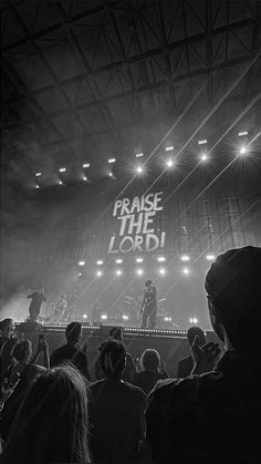 a black and white photo of people in front of a stage with the words praise the lord written on it