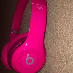 a pair of pink headphones sitting on top of a carpeted floor next to a wall