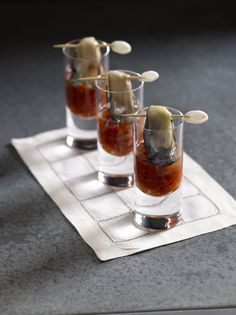 three shot glasses with toothpicks in them sitting on a napkin