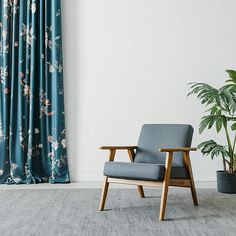 a chair sitting in front of a window next to a potted plant on the floor