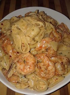 pasta with shrimp and sauce in a white bowl on a wooden table top, ready to be eaten