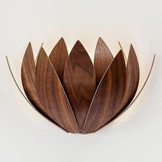 a wooden wall light that is shaped like a flower with leaves on the top and bottom