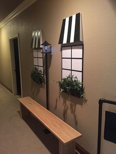 an empty room with two windows and a bench in front of the window that has plants on it