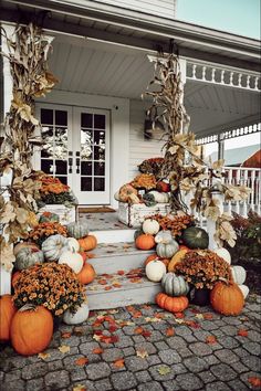 pumpkins and gourds are arranged on the front porch