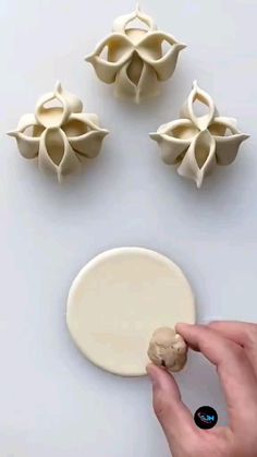 a hand is holding a piece of food in front of three pieces of pasta on a white surface