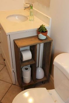 a white toilet sitting next to a wooden cabinet in a bathroom under a faucet