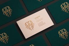 the business card is designed with gold foil on dark green paper and has an intricate monogram design