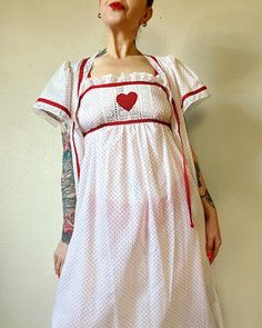 "Sweet Heart. Beautiful Deadstock Vintage 1970's/1980's Lanz of Salzburg red and white 2pc nightie set with heart appliqué, heart buttons, polka dots galore and lace trim. Perfect sweetheart ensemble. ♥️♥️♥️ Marked a vintage size M  Fits XS/S/M (I'm about a M), but please use measurements as fit guide.  Robe: 13.75\" shoulder  23\" bust (on the half) 8\" sleeve  56.25\" length  Unlined  Center front heart button closures and tie at neck  Cotton or cotton/blend  Flutter sleeve  Front patch pockets  Lace trim gathering at forward shoulder  Back yoke with gathering  Contrast polka dot binding  Nightgown: 15.5\"-19\" bust (on the half)  55\" length  Unlined  Slip on style  Cotton or cotton/blend  Attached tie at underbust  Elastic back  Lace trim  Heart appliqué at bust  Contrast polka dot bin Fitted Coquette Nightgown, White Fitted Dress For Pajama Party, White Cotton Dress With Heart Print, Vintage White Fitted Nightgown, White Fitted Vintage Nightgown, Fitted Retro Summer Sleepwear, Vintage Dresses For Pajama Party, Red Fitted Cotton Sleepwear, Fitted Red Cotton Sleepwear