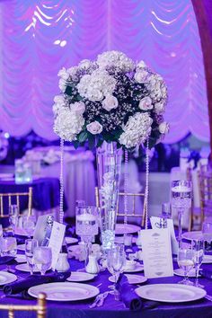 the table is set with white flowers and place settings