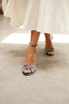 a close up of a woman's feet wearing sandals and a white dress with blue bows