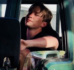 a man is sitting in the back seat of a truck looking out the window at something