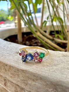 This 18ct yellow gold cluster ring features a stunning multicolor sapphire for a tot of .9ct with a stunning blue sapphire at its center and one radiating emerald (.11ct) for a colorful eye-catching look. Expertly set in a timeless classic yellow gold, bringing a colorful touch to your everyday style. Available in Size 6.5US and can be adjusted to fit your requested size. Please leave your comments at checkout 1 piece is available of this ring & cannot be replicated due to the availability/rarity of the stone/cut/ct weight. Metal: Genuine authenticated solid 18Kt yellow gold Not plated or filled or vermeil 750 Stamped for authenticity Gemstone: Multicolor Sapphire tot .90ct Emerald 0.11ct Handcrafted in Dubai If you wish to customize same ring with a similar/different stone please get in t Multicolor Sapphire Multi-stone Ring, Multicolor Multi-stone Sapphire Ring, Multicolor Sapphire Ring In Fine Jewelry Style, Multicolor Oval Sapphire Ring, Multicolor Cluster Fine Jewelry, Multicolor Sapphire Ring With Prong Setting, Multicolor Sapphire Gemstone Ring, Multi-stone Sapphire Ring For Promise, Multicolor Round Sapphire Gemstones