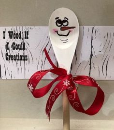 a wooden spoon with a red ribbon tied around it on top of a white sign