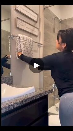 a woman in black shirt and leggings standing next to a bathroom sink with toilet paper on the wall