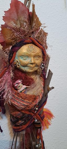 a sculpture made out of cloth and wire with leaves on it's head, sitting on top of a table