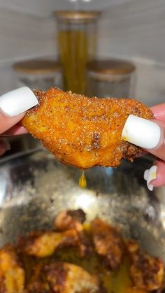 a person holding food in their hand over a pan with other food items on it