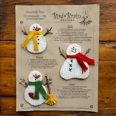 three snowmen made out of felt sitting on top of a piece of paper