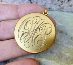 a person holding a gold locke with the letter h on it's front side