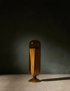 a brown vase sitting on top of a table next to a black wall and floor