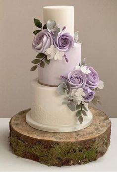 a three tiered wedding cake with purple flowers on top