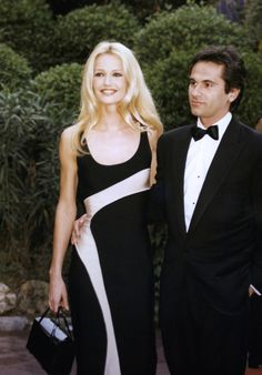 a man in a tuxedo standing next to a woman wearing a black and white dress