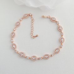 the rose gold bracelet is adorned with swaro - cut stones and has a chain that wraps around it