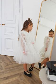 Introducing our delightful tulle dress for girls! With a skirt that falls just below the knee, adorned with a tulle ruffle, this dress exudes charm and elegance. The airy tulle long sleeves add a touch of whimsy to the ensemble, making it simply enchanting. Order your dream dress now by submitting a request on the website or contacting our professionals at the provided phone number. Our consultants will be happy to help you choose the perfect size and color scheme for your little princess. All our dresses are handmade and tailored exclusively after your order, so we can work together to choose the organza print for the dress or make any adjustments you desire. Let your celebration be filled with magic and memories with the wonderful children's festive dresses from Manashakids! The accessor Cute Princess Dress With Long Sleeves In Tulle, First Communion Princess Dress With Ruffles, Ruffled Tutu Dress For First Communion, Princess Style Tulle Tutu Dress For First Communion, Long Sleeve Tulle Princess Dress For Birthday, Long Sleeve White Princess Dress For Birthday, White Long Sleeve Princess Dress For Birthday, Long Sleeve Tulle Tutu Dress For Birthday, Princess Style Organza Tutu Dress For Baptism