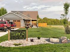 a red truck is parked in front of a house with a yard sign and landscaping