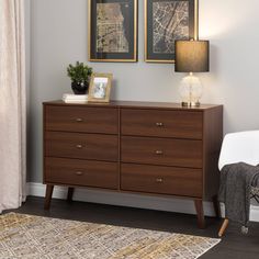 a bedroom scene with focus on the dresser and two framed pictures hanging above it's headboard