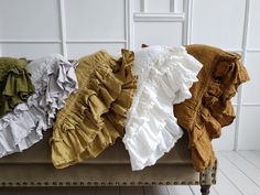 four different colored ruffles on a bench in front of a white wall and wood floor