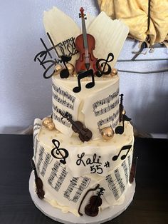 a three tiered cake with musical notes and violin on it's side, sitting on a table