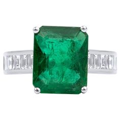 an emerald and diamond ring with two baguets on the side, set in white gold