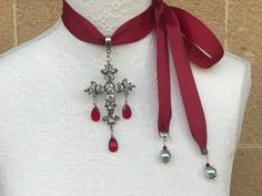 Cross necklace with red drop facetted glass crystals on grosgrain tie ribbon. Can be worn in many ways, as choker or as pendant, depending on you you tie the ribbon. The cross is antique silver in zinc alloy, has facetted glass stones. The neck band dark red grosgrain 2.5cm or 1 inch width. Red facetted tear drop glass. Measurements are as follows: Cross height is 8cm Cross width is 5.5cm Total length of pendant including bail and red drop crystal is just under 12cm I can customise the necklace Elegant Silver Cross Choker, Elegant Cross Choker As A Gift, Goth Victorian, Cross Choker Necklace, Layered Pearl Necklace, Cross Choker, Tie Ribbon, Large Pendant Necklace, Mens Leather Sandals