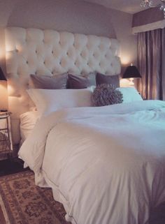 a large white bed sitting in a bedroom next to two lamps on either side of the bed