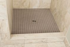 a tiled shower stall with a square hole in the floor and tile on the walls