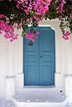 a blue door with pink flowers growing over it's sides and below the doors