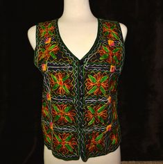 This vest is an embroidered vest with floral pattern and small mirrors woven into it. It reminds me of an El Matador vest Would work great for an ugly Christmas sweater party or for a Halloween costume, Mardi Gras or just getting back to your roots! DETAILS Condition: Good MEASUREMENTS Size on tag: Women's Large could work for men also Back of neck to Bottom: 19.5" Armpit to Armpit: 18.5" All measurements are taken flat across garment. For most accurate size please double check measurements against one of your own garments. Vintage sizes vary from modern sizes.  I am happy to provide any other measurements you need - just ask!! This item is pre-worn but is in good condition.  Any piling or imperfections are part of the charm and character of the item and should be taken into consideration Embroidered Sleeveless Vest For Fall, Sleeveless Embroidered Vest For Fall, Multicolor Vest Tank Top For Festival, Fall Festival Sleeveless Tank Top, Embroidered Sleeveless Party Top, Sleeveless Vest For Fall Festival, Sleeveless Top With Multicolor Embroidery For Party, Sleeveless Multicolor Embroidered Top For Party, Sleeveless Multicolor Embroidered Party Top