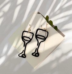 two wine glasses are sitting on top of a piece of paper next to a plant