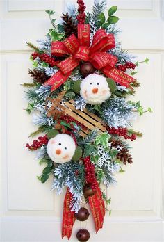 a christmas wreath with two snowmen and pine cones hanging on the front door,