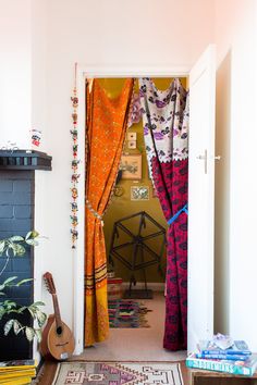 an open door leading to a living room with colorful curtains and rugs on the floor