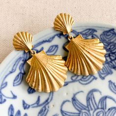 Gorgeous gold plated shell post with a lightweight shell drop. The perfect coastal accessory! 14k gold plated brass approx. 2" Gold Brass Shell-shaped Earrings, Gold Shell-shaped Brass Earrings, Elegant Shell-shaped Brass Jewelry, Gold-plated Shell-shaped Earrings, Gold Plated Shell-shaped Earrings, Gold Brass Shell Earrings, Gold Shell-shaped Metal Earrings, Gold Shell Drop Earrings, Ocean-inspired, Gold Ocean-inspired Shell Drop Earrings