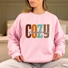 "Stay Cozy Sweatshirt,Winter Shirt,Let's Get Cozy T shirt,Cozy Cuddles Tshirt,Fall Quotes T-shirt,Cozy Season Apparel,Cold Weather Tee, Thank you so much for taking the time to browse my shop. Please feel free to reach out if you have any questions before or after purchasing.  💖 🎨Warning: On products with a print chart in the listing, metallic print colors are printed as matte. We design and cut each graphic out with a soft touch, use matte vinyl and a heat press. The result will last for many washes. PRODUCT DESCRIPTION: Our sweatshirt are super comfortable and the quality is excellent, they are manufactured with cotton fibers to ensure comfort and durability. Polyester fibers are extremely strong, and resistant to most chemicals, along with shrinkage. 50% cotton, 50% polyester. The siz Pink Cozy Crew Neck Hoodie, Cozy Pink Crew Neck Hoodie, Cozy Pink Graphic Print Top, Cozy Pink Top With Graphic Print, Winter Loungewear T-shirt With Ribbed Cuffs, Comfortable Pink Winter Tops, Cozy Letter Print Hoodie Sweatshirt, Pink Letter Print Sweats For Winter, Pink Winter Sweats With Letter Print