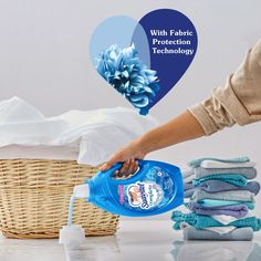 a woman is pouring water into a basket with folded towels and blue flowers on it