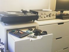 a record player sitting on top of a white dresser next to a monitor and keyboard