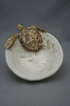 a ceramic turtle sitting on top of a white bowl