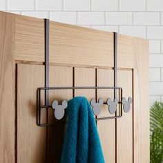 a towel rack with mickey mouse magnets on it next to a blue towel and potted plant